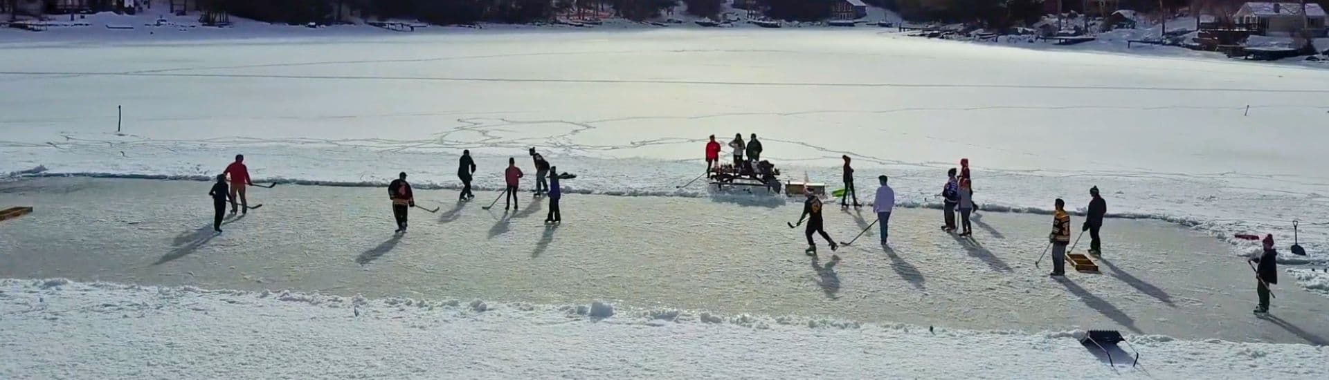 People ice skating on a frozen lake surrounded by snow.