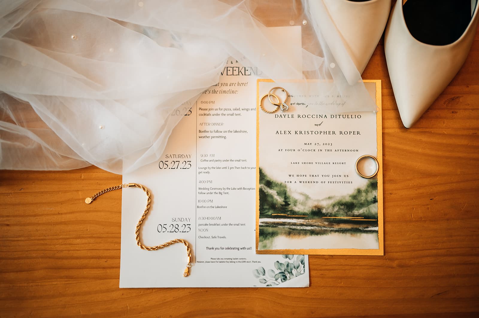 Wedding invitation and schedule with rings, jewelry, and shoes on a wooden surface.