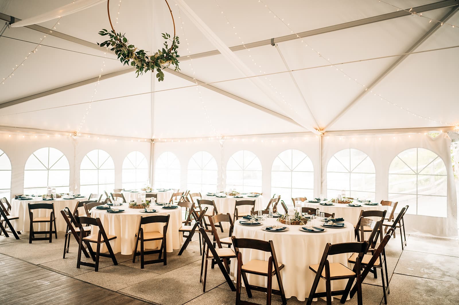 A beautifully arranged tent interior with tables, chairs, and soft lighting for an event.