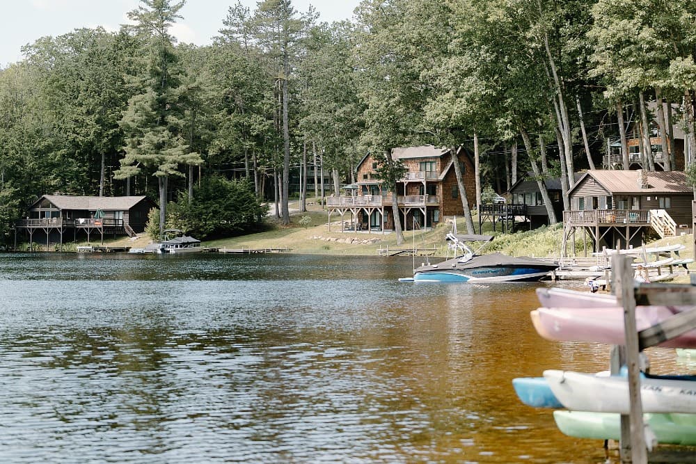 A serene lake scene featuring rustic cabins and colorful kayaks along the shore.