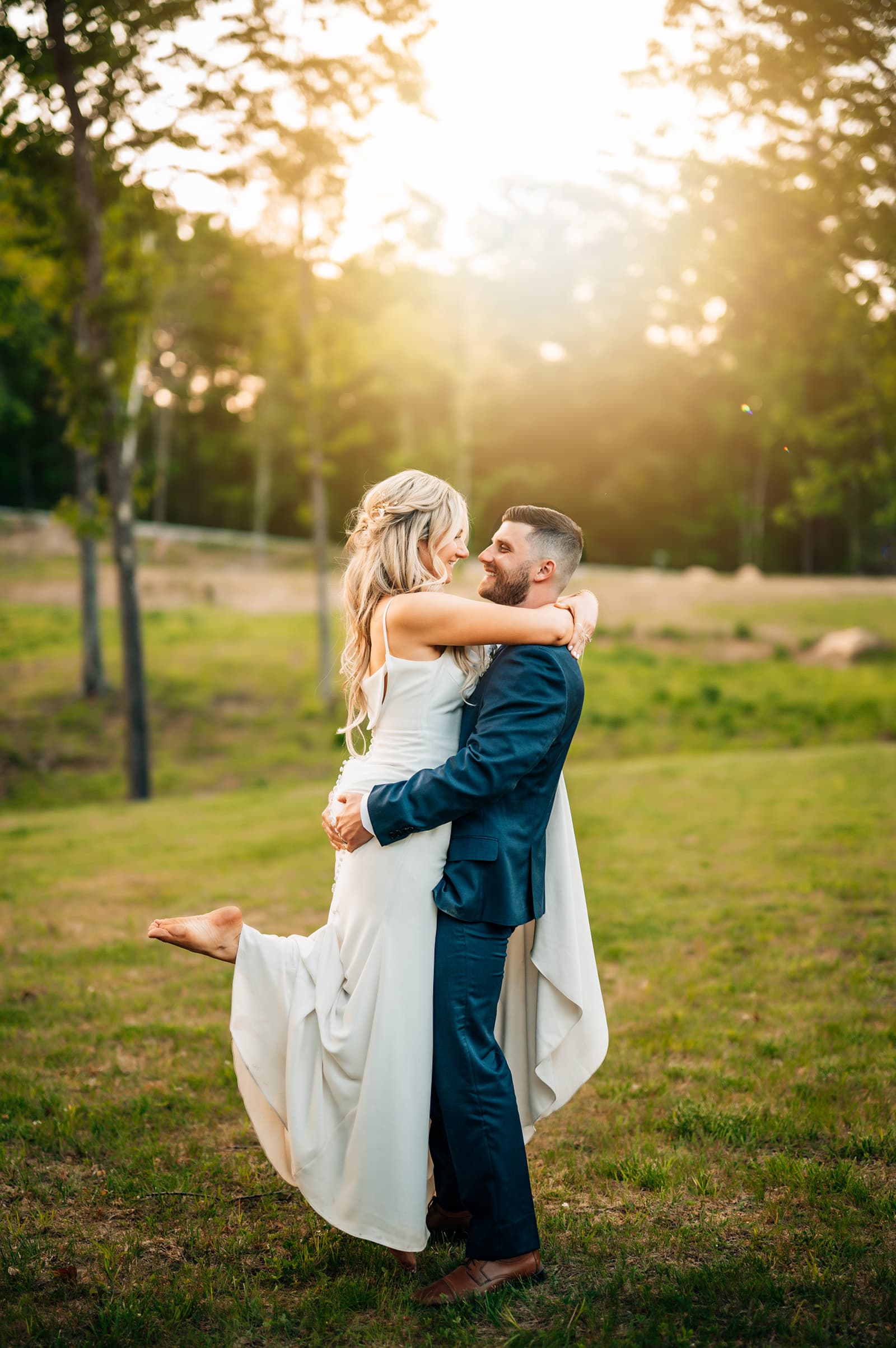 A couple embraces joyfully in a sunlit outdoor setting.