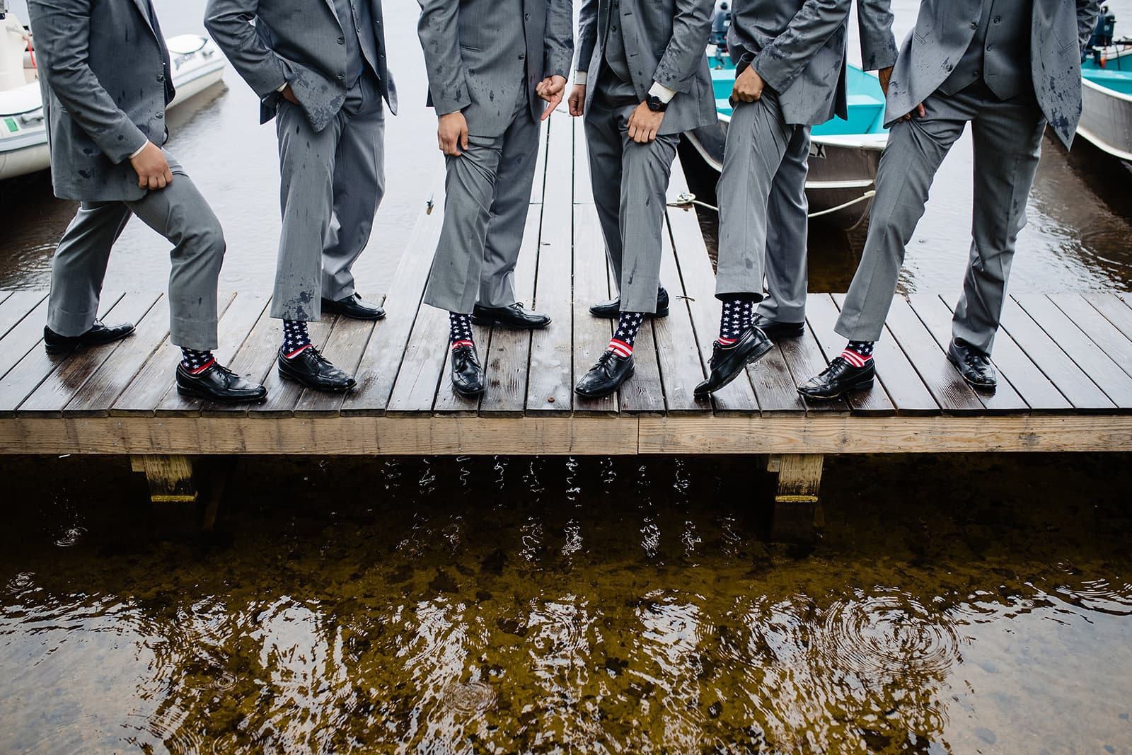 A group of men in gray suits stand on a dock, showcasing mismatched colorful socks.